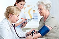 A patient gets there blood pressure taken while two nurses look on