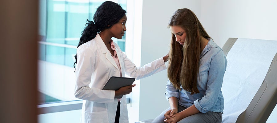doctor consoling young woman