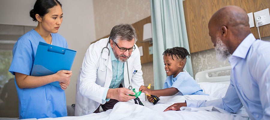 Child patient in hospital bed with doctor playing