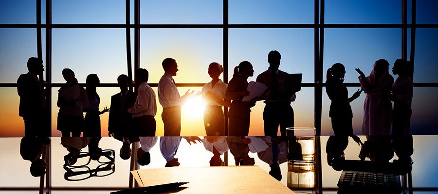 business people in silhouette in front of sunset window