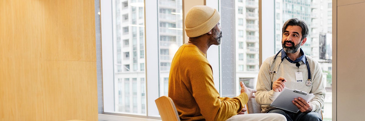 Physician and patient, both male, sit talking in a room
