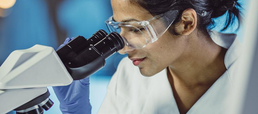 Tech examining cells through microscope