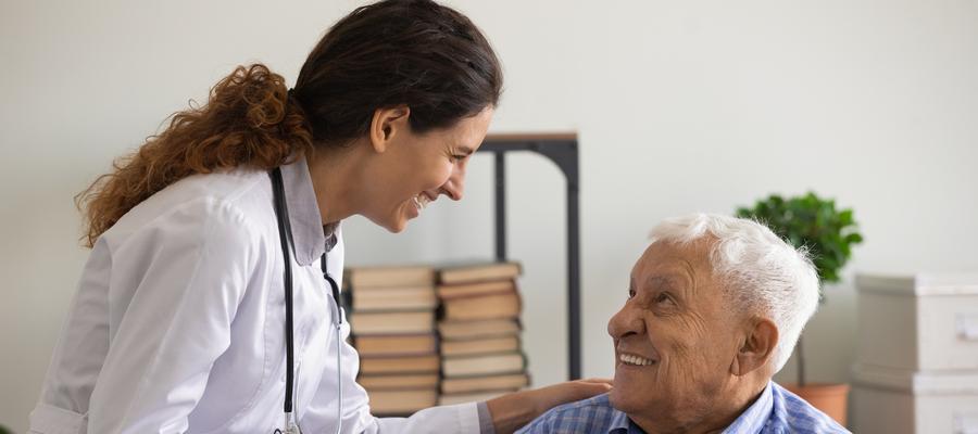 An older man laughs with a younger female doctor